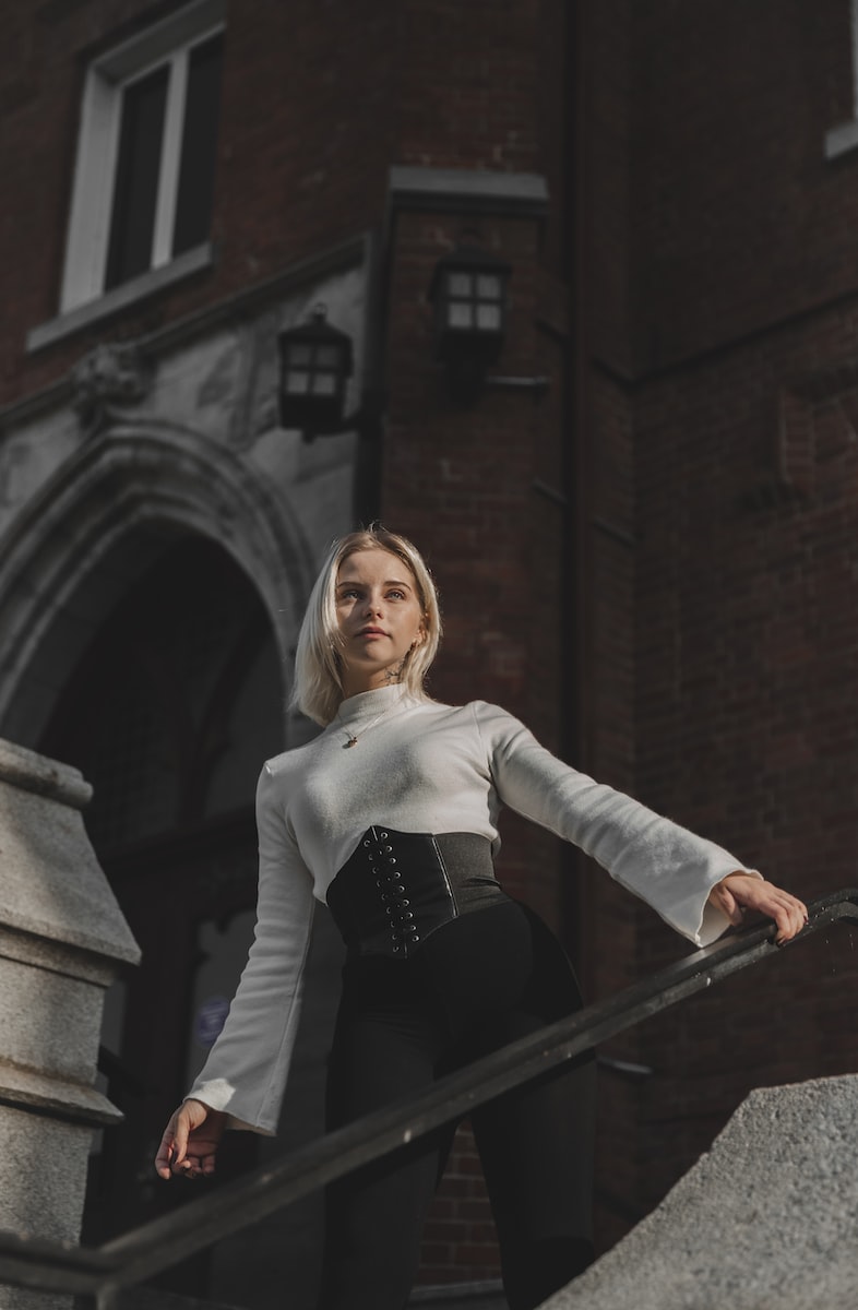 woman in white long sleeve shirt and black skirt standing on stairs